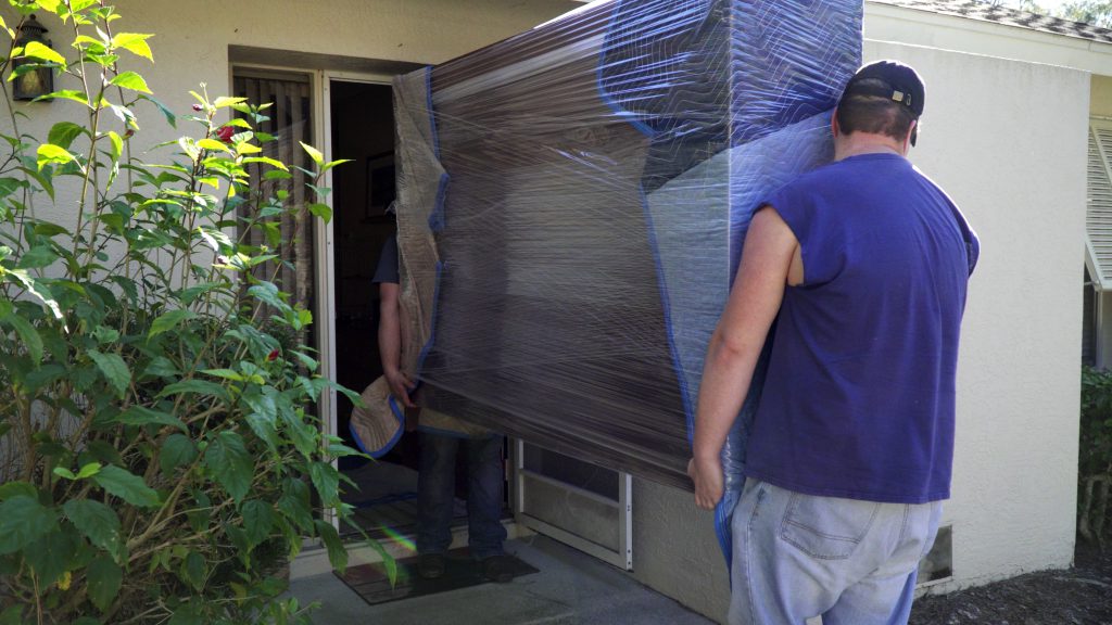 Two movers lift a hutch through a pre-measured doorway.