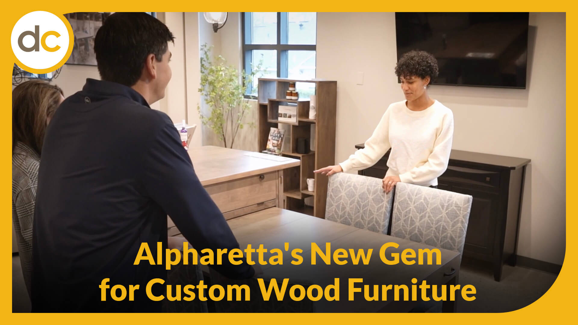 a furniture specialist and customers stand around an Amish made table with the title Alpharetta's New Gem for Custom Wood Furniture
